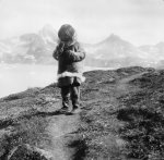 [Greenland child on coastal path with sea and mountains in background]
